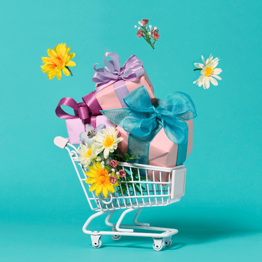 Mini shopping cart filled with gift boxes and flowers against a turquoise background.